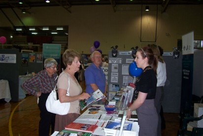 A photograph of the Consumer protection booth at the Seniors expo Bunbury  (shot side on) with the staff handing out  WA ScamNet balloons.