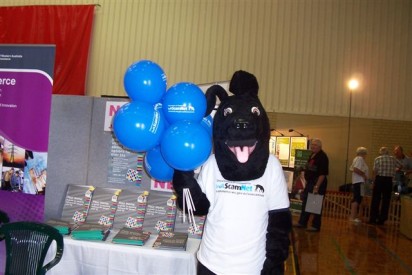 A photograph of the Consumer protection booth at the Seniors expo Bunbury with Jet holding WA ScamNet balloons.