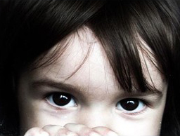 A sad little girl looking at you over her fingers