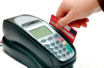 A hand swiping a credit card though an eftpos machine