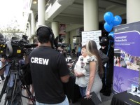 A shot of the booth at the ScamNet launch showing the media interviewing the scam victim with camera crews